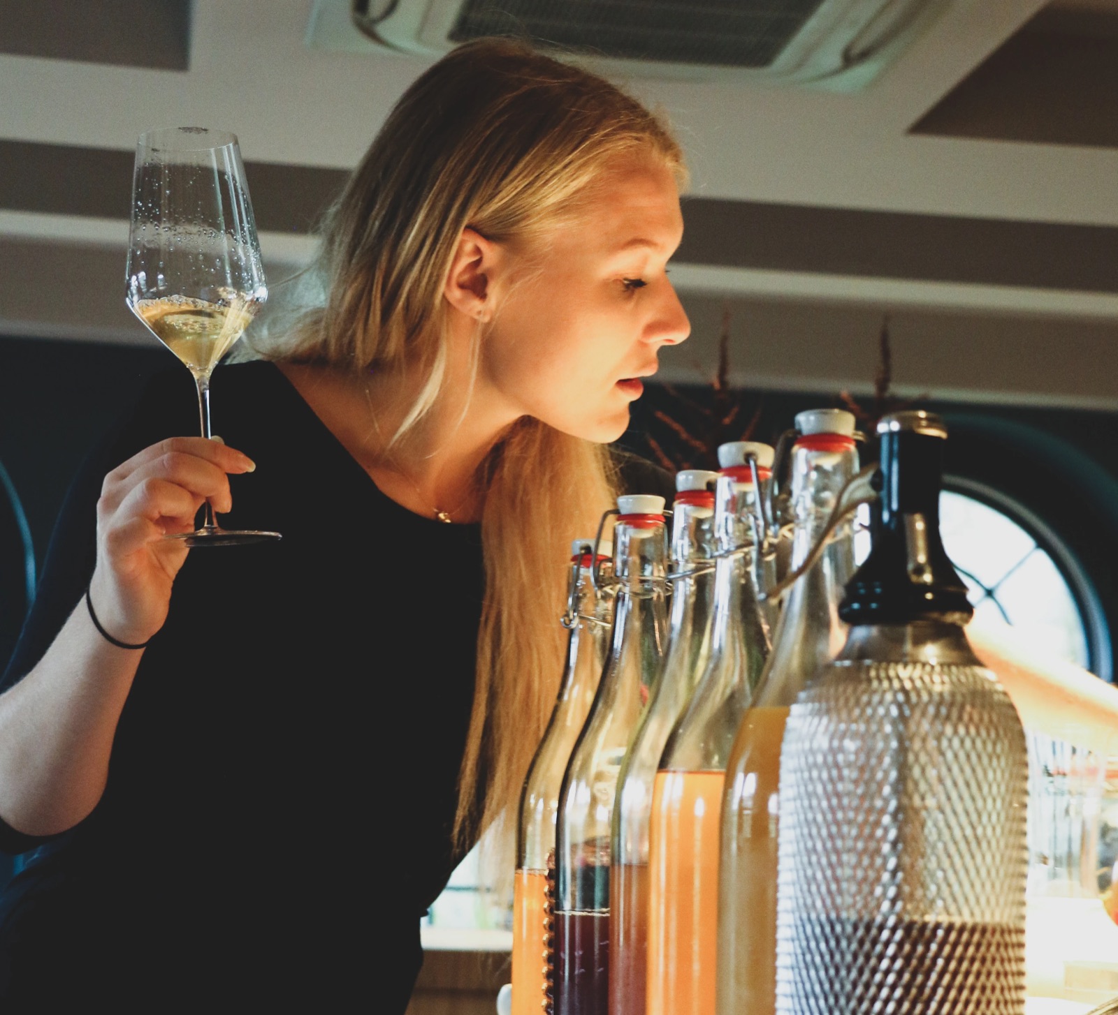 Majken Bech-Bailey examining a glass of wine over a row of house-made infusions